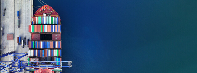 Aerial drone ultra wide top down photo of industrial cargo container ship being loaded by large...