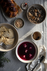 Essential Ukrainian Christmas Eve supper dishes - borsch with vushka (porcini dumplings), varenyky, kutia, uzvar on linen tablecloth.  