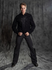 an attractive man in an elegant suit, shirt with embroidery. Photo in the studio on a gray...