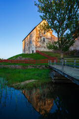 Fototapeta premium Medieval Kastelholm Castle, its reflections and a wooden pier in Åland Islands, Finland, at sunset in the summer.