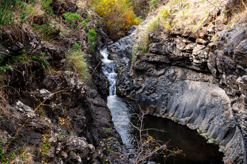 Mountain stream Meshushim. Nahal Meshushim. Rocks in the form of hexagonal basalt columns.