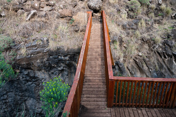 Bridge over the mountain stream Meshushim. Nahal Meshushim. Rocks in the form of hexagonal basalt...