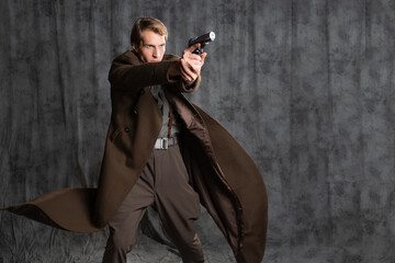 hero in a military style with a gun in his hands, a young man in a long brown coat and breeches with suspenders. he shoots a pistol in a spectacular pose, his coat flutters behind his back
