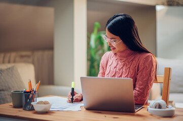 Vietnamese Asian woman using laptop while working at home