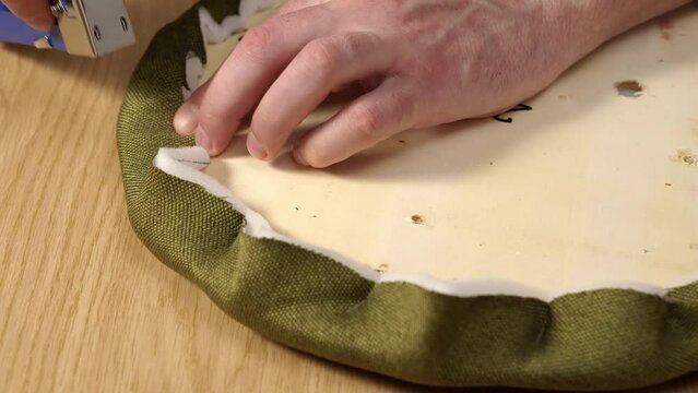 Furniture restoration. A man fixes the paralon on the surface of the chair with a stapler. Upholstery of furniture. Close-up hands