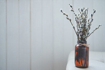 Willow branches in a bouquet on the edge of the table. Willow, fluffy buds, brown glass vase. Palm Sunday Holiday with copy space. High quality photo