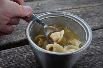 Chicken Noodle Soup in a Stainless Thermos on Weathered Picnic Top