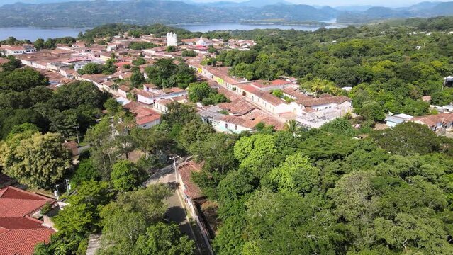 Vista a&eacute;rea de pueblo colonial con monta&ntilde;as, lago y &aacute;rboles