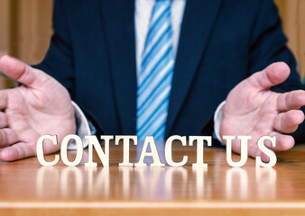 CONTACT US letters on desk between welcoming hands of business person. 