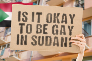 The question " Is it okay to be gay in Sudan? " is on a banner in men's hands with blurred background. Friendly. Passionate. Contact. Date. Dating. Lover. Partner. Boyfriend. Pleasant. Approval