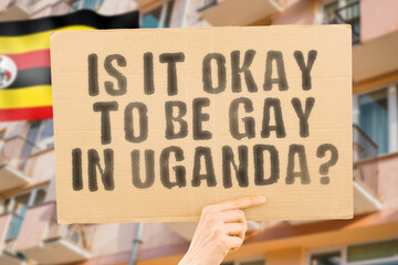 The question " Is it okay to be gay in Uganda? " is on a banner in men's hands with blurred background. Friendly. Passionate. Contact. Date. Dating. Lover. Partner. Boyfriend. Pleasant. Approval
