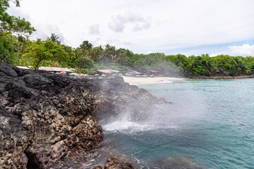 Beautiful nature fountain near Bias Tugel beach at the south of Bali island. White sand and rock shore.