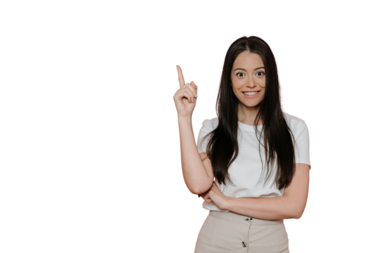 Cheerful pretty brunette in white t-shirt, beige skirt, points upward by index finger, in amazed mood, enjoys life, ready for summertime. Stands over transparent background. Sale and promotion concept