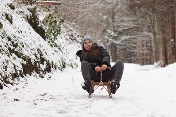 Mädchen fährt Schlitten schnell den verschneiten Berg herunter