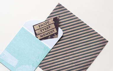 tiny note with message: Enjoy Every Moment and pocket envelope on scrapbook paper with stripes