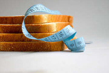 Piece of white bread measuring tape on a light background