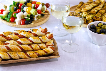 Przekąski na przyjęcie sylwestrowe lub karnawał: kabanosy we francuskim cieście, paluszki z ciasta francuskiego i pesto, szaszłyki z pomidorami, oliwkami i serem serwowane z białym winem