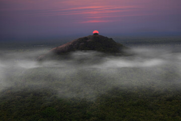 View from Sigiriya Sri Lanka to Pidurangala mountain. Path up the hill for tourists to climb the Lion Rock. Athmosphere with haze.