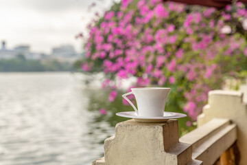 In Hanoi, Vietnam, a coffee cup by Hoan Kiem lake in the morning. Concept of inspiration and relaxing. Shallow focus on the top of the cup's handle.