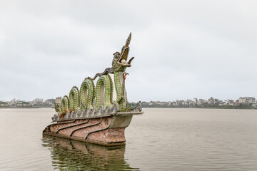 In Hanoi, Vietnam, the famous Twin Dragons of West Lake monument. City skyline beyond.