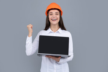 Business builder woman with laptop computer, portrait on gray. Portrait of female worker in hardhat helmet.