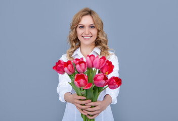 blond woman smile with spring tulip flowers on grey background