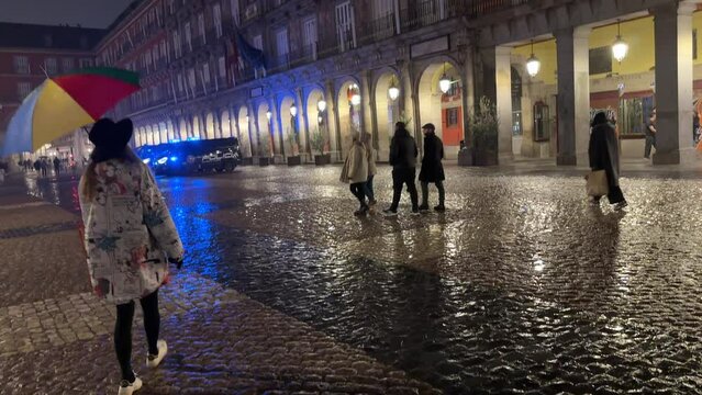 Gente caminando en la noche con lluvia en la plaza mayor de Madrid