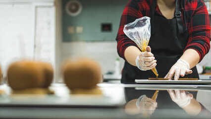 Unrecognizable pastry chef using pastry bag - sac a poche - in bakery kitchen. Copy space. Blurred...