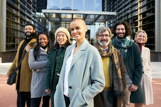 A group of smiling business people from a company led by an empowered shaved air woman. Cheerful Looking at camera portrait of a group of happy co-workers of diverse races and ages. High quality photo