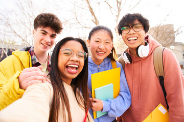 Obraz premium Selfie of Four international students with beaming smiles are posing for photo shot, latin attractive lady is taking, in school library and folder. Gathered, cheerful, smart and successful youth