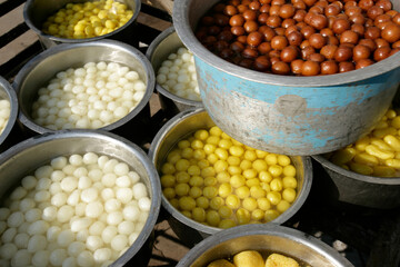 Indian sweets stacked in large tin bowls.