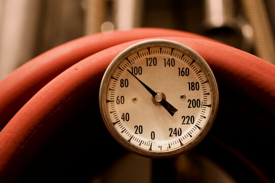 Temperature gauge with red hose in a brewery.