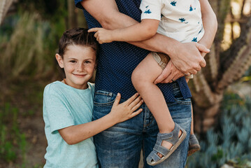 Mid view of elementary age boy hugging father and brother and smiling