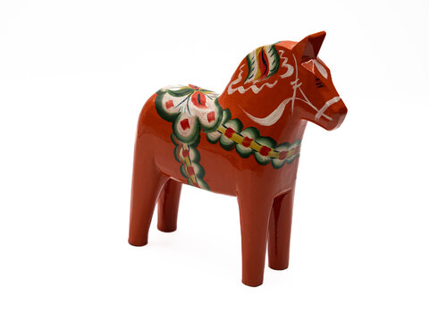 Traditional Swedish Dala Horse (Dalahäst) painted in many colors seen from the front and side against white background.