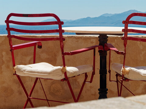 Red chairs facing greek sea