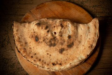 calzone pizza on wooden plate top view.