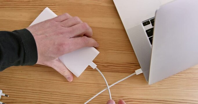 Unplug the power cord from the outlet and connect the charged drive to your laptop. Alternative power supply for a laptop during a power outage, close-up.