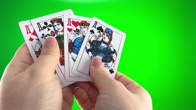 female hands with french manicure. woman sorts through cards, examines them folds and spreads out like fan four cards left of same suit Hand holding four Card Queen on a green background close-up