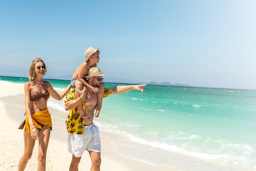 Joyful father, mother and son walking on the sandy tropical beach. Happy family holidays.  Active...