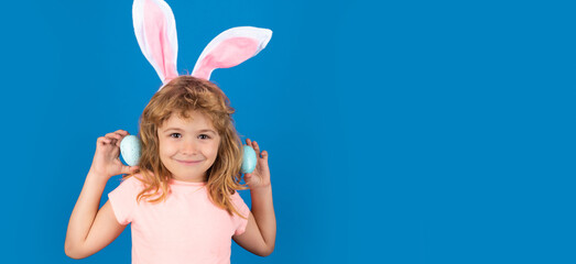 Happy Easter. Kids boy in bunny ears hunting easter eggs isolated on blue background. Wide photo...