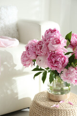Bouquet of beautiful peonies on pouf indoors