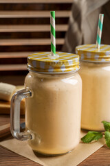 Tasty banana smoothie and mint on wooden table
