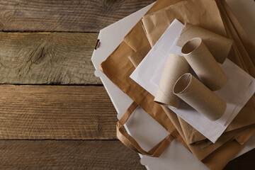 Stack of different waste paper on wooden table, flat lay. Space for text