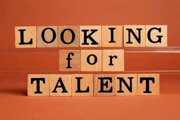Recruitment and hiring concept. Phrase Looking For Talent made of wooden cubes on orange background