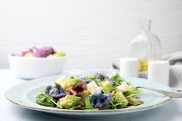 Delicious salad with cauliflower and pumpkin seeds served on white tiled table, closeup