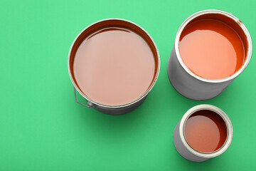 Cans of orange paint on green background, top view