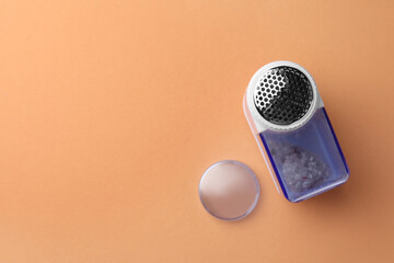 Modern fabric shaver with fuzz on pale orange background, flat lay. Space for text