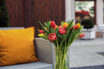 Beautiful bouquet of colorful tulips in glass vase outdoors