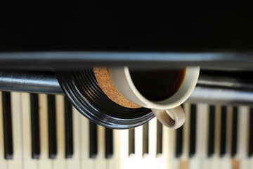 Cup of delicious coffee on grand piano, closeup