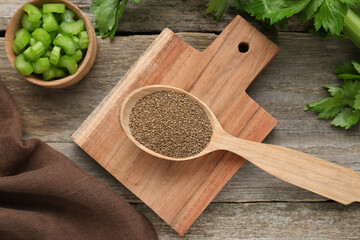 Spoon of celery seeds and fresh plant on wooden table, flat lay